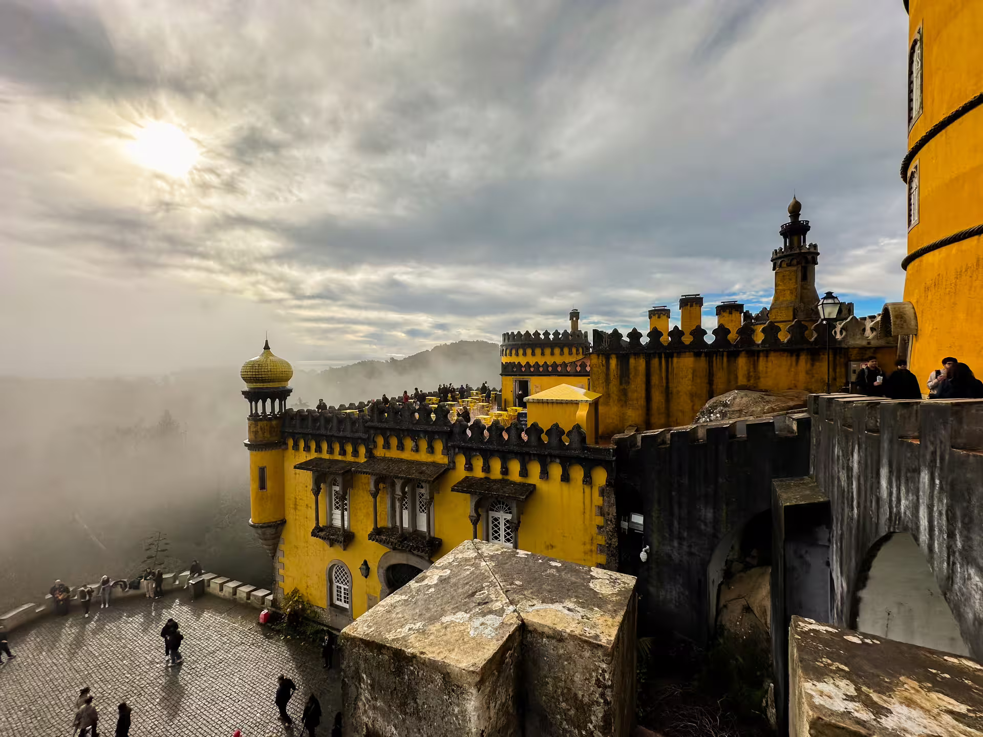 Stunning view of Pena Palace in Sintra surrounded by mist during a private van tour, showcasing its vibrant architecture.