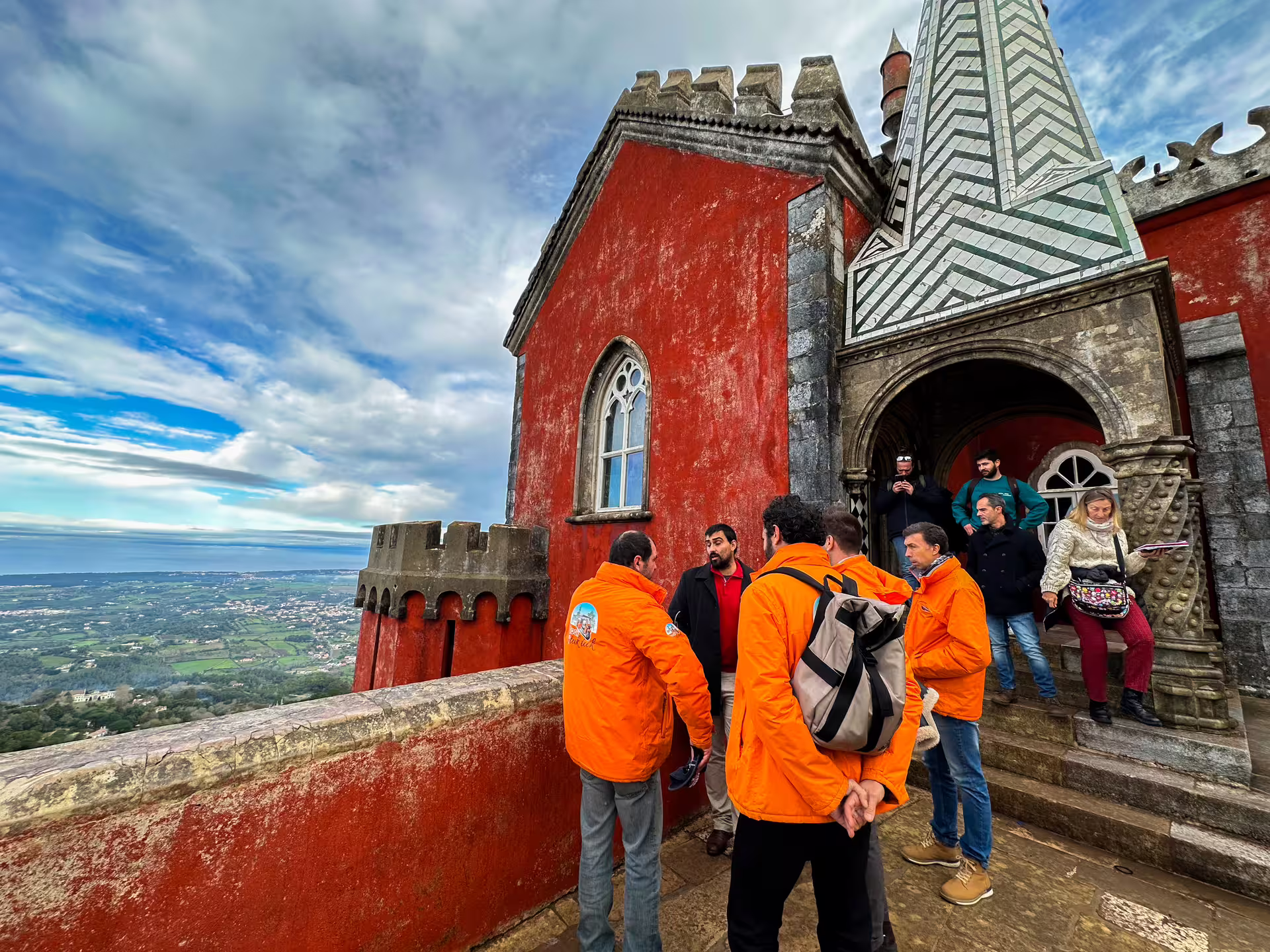 Tourists admire the vibrant red facade of Pena Palace with stunning views during a Sintra private van tour.