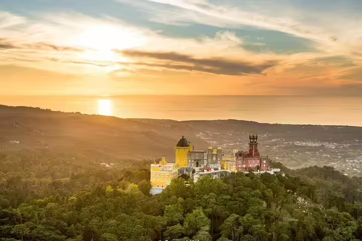 Stunning aerial view of Pena Palace in Sintra, Portugal during sunset, highlighting the lush landscape on a private tour from Lisbon.