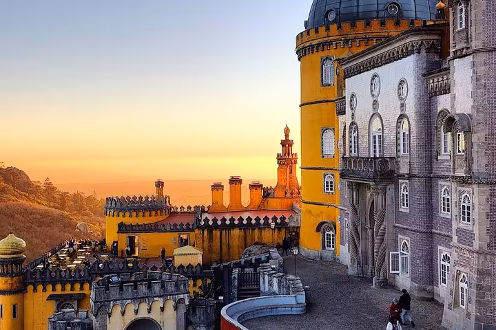 Sunset illuminating the stunning Pena Palace in Sintra, showcasing its vibrant hues and detailed architecture.