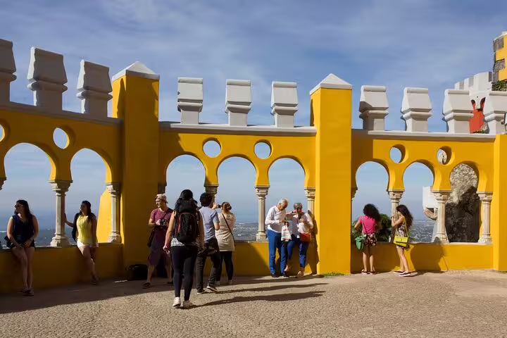 Visitors explore the vibrant yellow walls and stunning views at Pena Palace, a highlight of the Sintra day tour with Regaleira.
