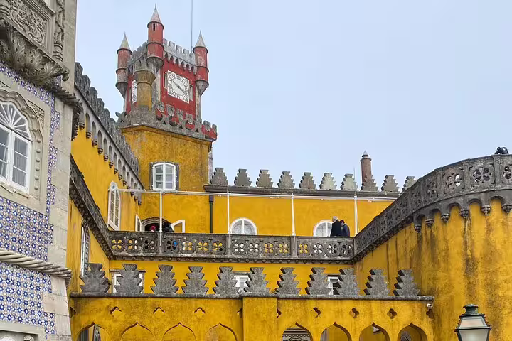 Explore the vibrant yellow facade and clock tower of Pena Palace on the Full Day Tour Magic Sintra & Cascais.
