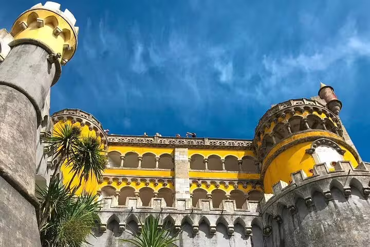 Vibrant yellow facade of Pena Palace against a clear blue sky, highlighting its unique architecture on a Sintra Mountain tour.