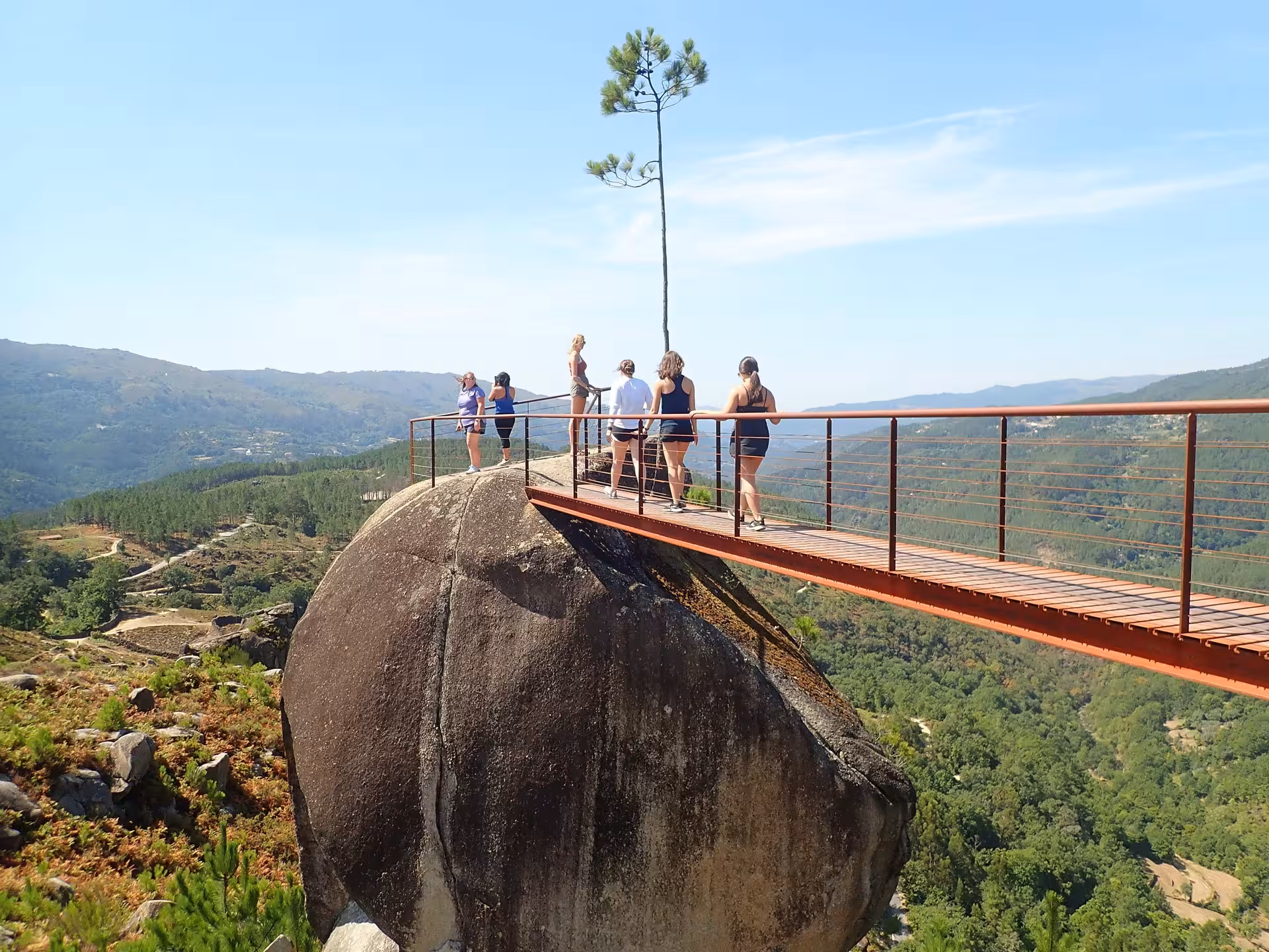 Tourists on a scenic bridge overlook stunning landscapes during a Peneda-Gerês National Park tour adventure.