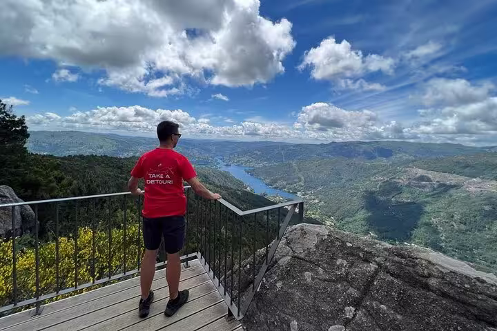 Tourist enjoying panoramic mountain and river views from a lookout point in Peneda-Gerês National Park.