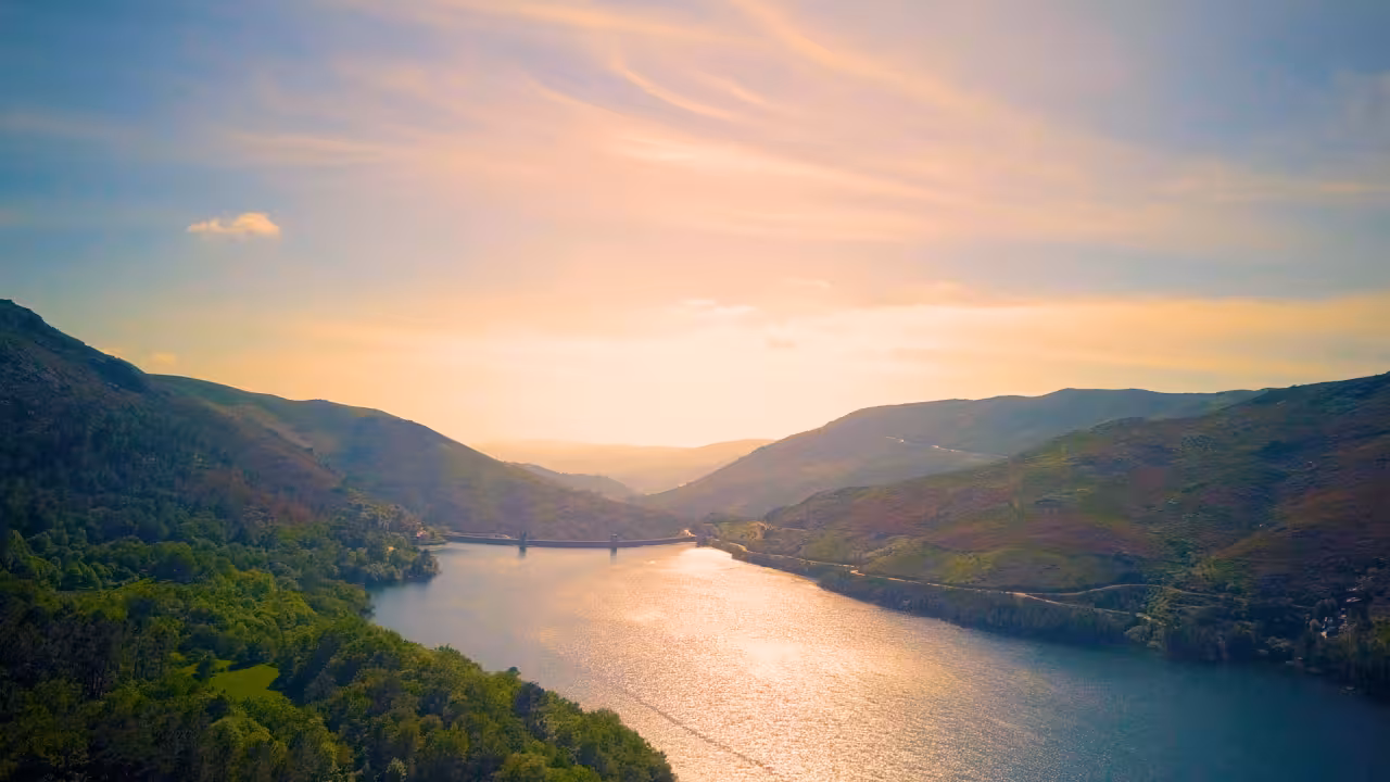 Scenic sunset view of Peneda Geres National Park with a tranquil river flowing between green mountains.
