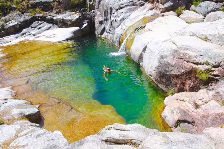 Visitor enjoying a refreshing swim in a crystal-clear natural pool at Peneda-Gerês National Park, perfect for private tours.