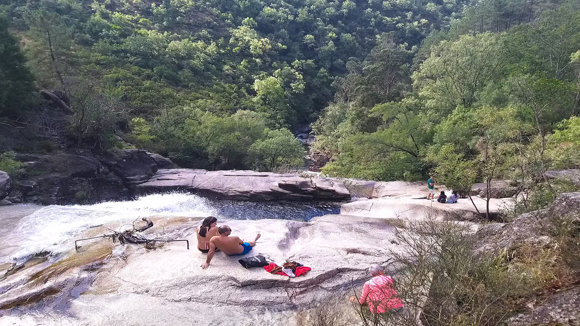 Visitors enjoy a scenic waterfall and lush greenery on a private tour in Peneda-Gerês National Park, perfect for nature enthusiasts.