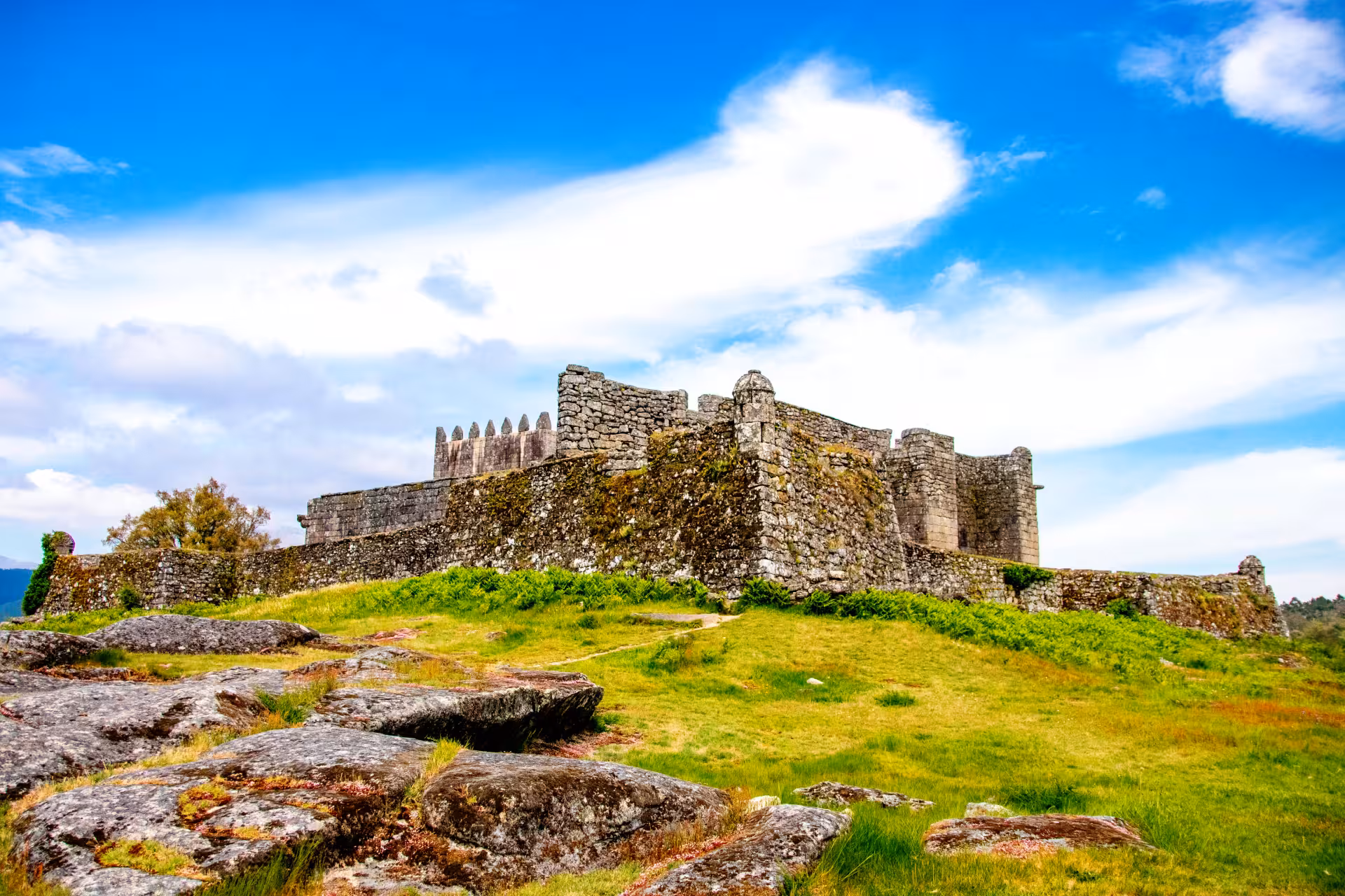 Explore the historic ruins of a stone castle under a vibrant blue sky in Peneda Geres National Park tour.