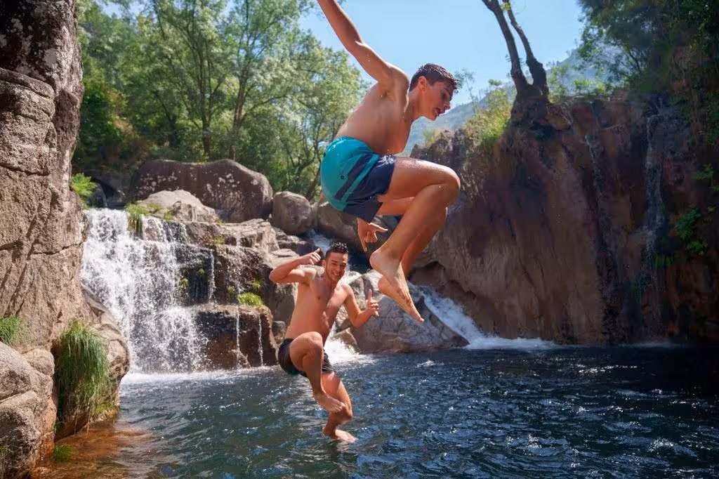 Adventurous jump into refreshing waters near a waterfall in Peneda-Gerês National Park, ideal for thrill-seekers.