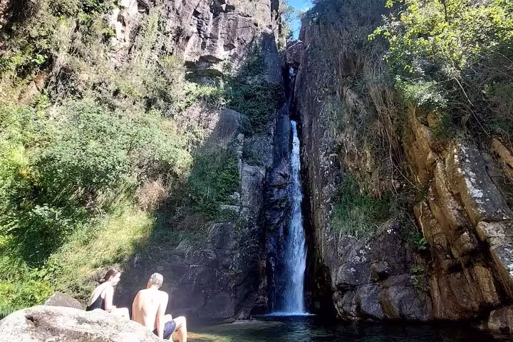 Tourists relaxing by a scenic waterfall in Peneda Geres National Park on a private tour from Porto.