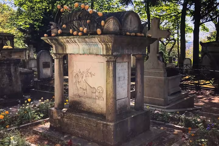 Ornate stone tomb with carved decorations and columns at Pere Lachaise Cemetery, Paris