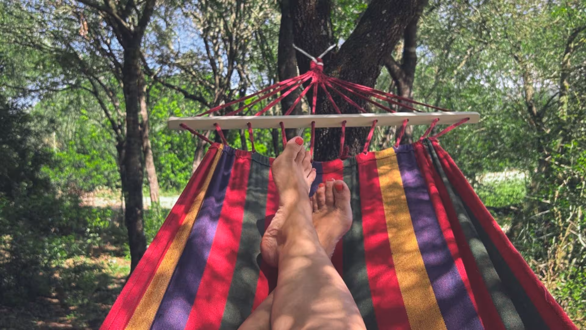 Relaxing in a colorful hammock under shady trees at Perfugas glamping, offering a serene nature escape.