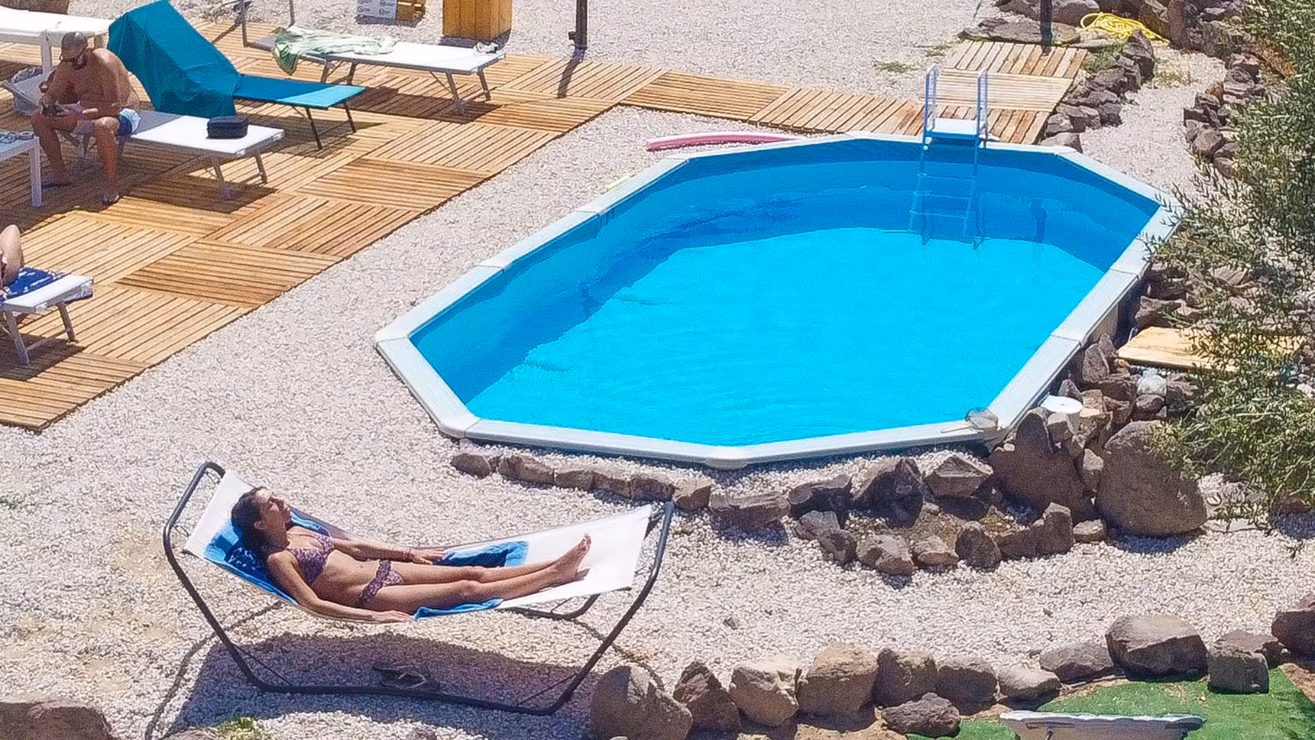 Relax by the sparkling pool at Perfugas glamping, surrounded by nature and sunbeds on a wooden deck.