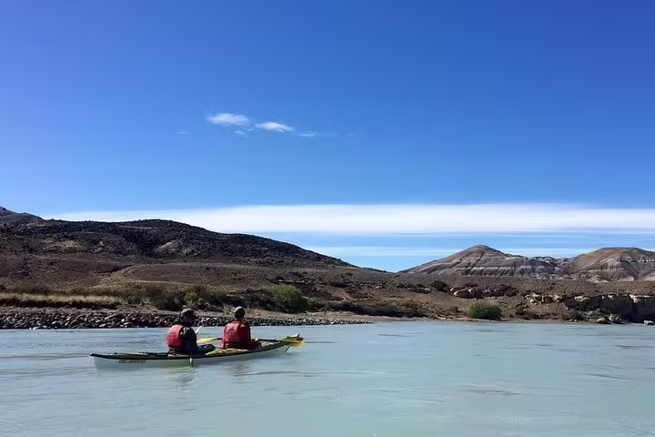 Two kayakers enjoy serene waters of La Leona River with scenic mountain views in El Calafate kayak adventure.