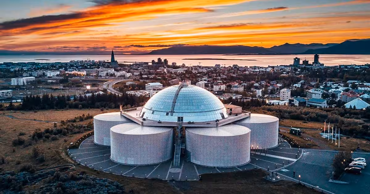 Aerial sunset view of Perlan museum dome overlooking Reykjavik cityscape on a private Iceland city tour