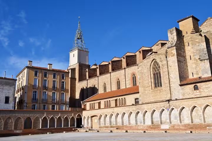 Historic Perpignan cathedral and arcaded square on a sunny day with blue sky
