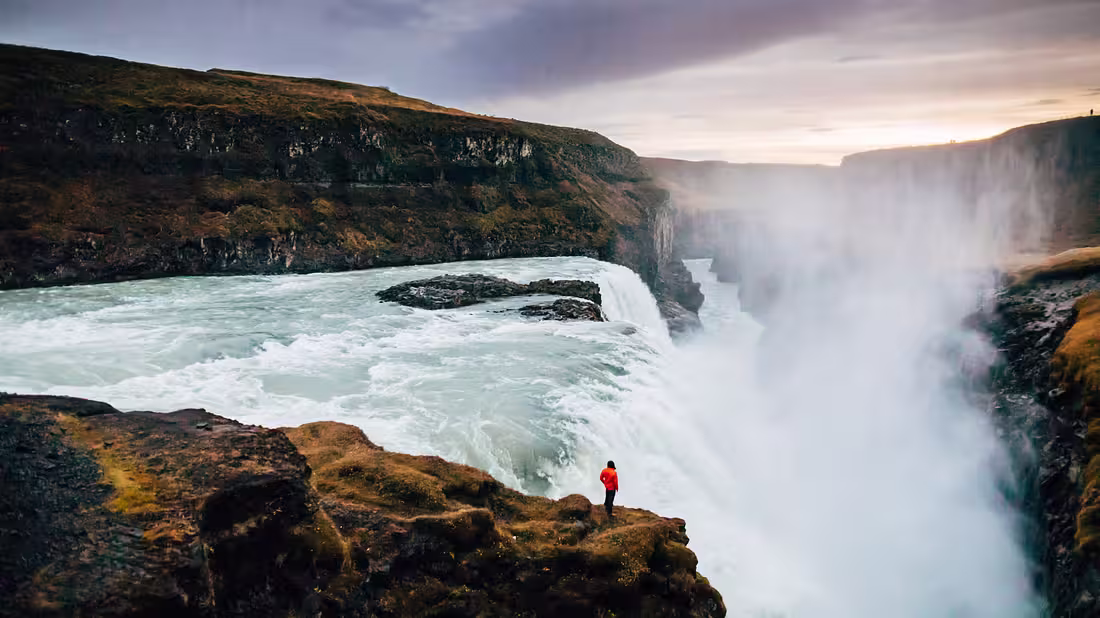 A person standing on close to a gigantic waterfall