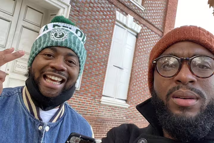 Two men smiling in front of historic brick building at Philadelphia Independence Historical Park