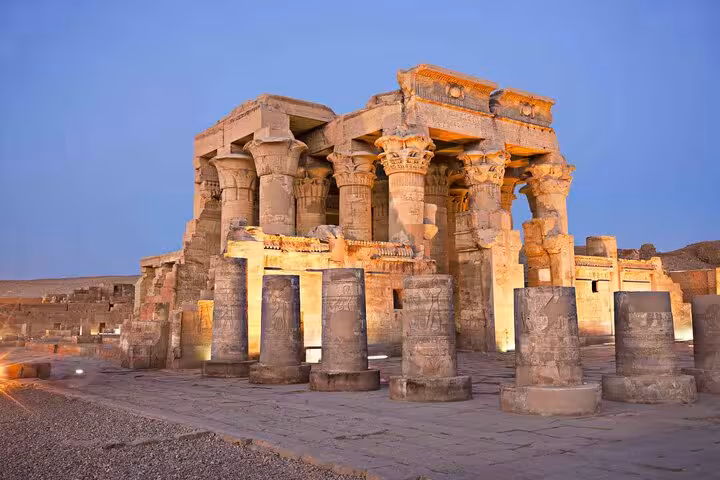 Illuminated Philae Temple columns at dusk in Aswan on a private day tour from Luxor with guide