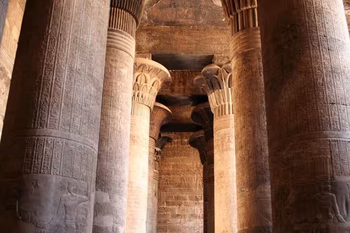 Inside Philae Temple columns with hieroglyphs, Aswan stop on Luxor to Abu Simbel overnight tour package