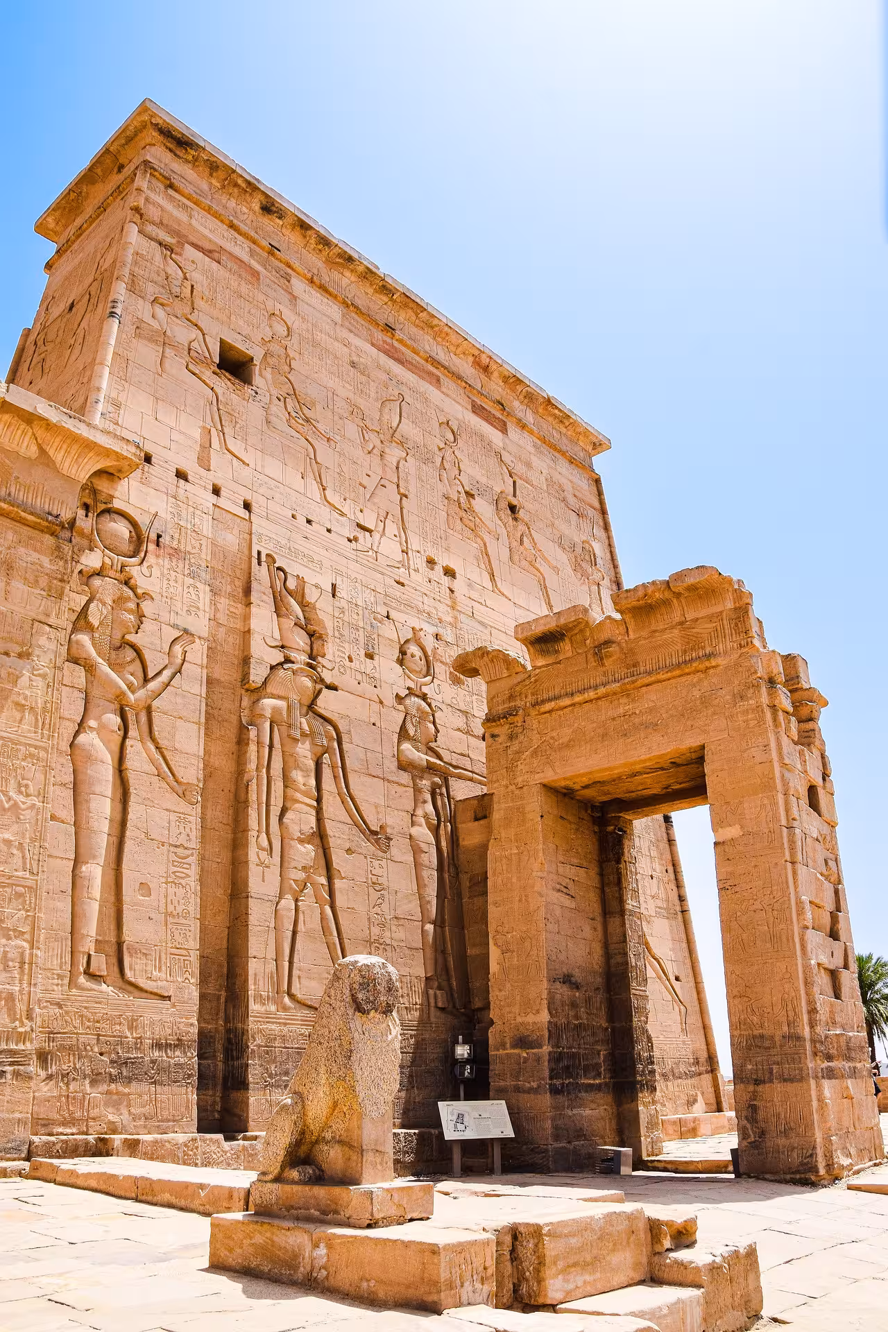 Ancient Egyptian hieroglyphics and deity carvings on Philae Temple pylon facade in Aswan, Egypt