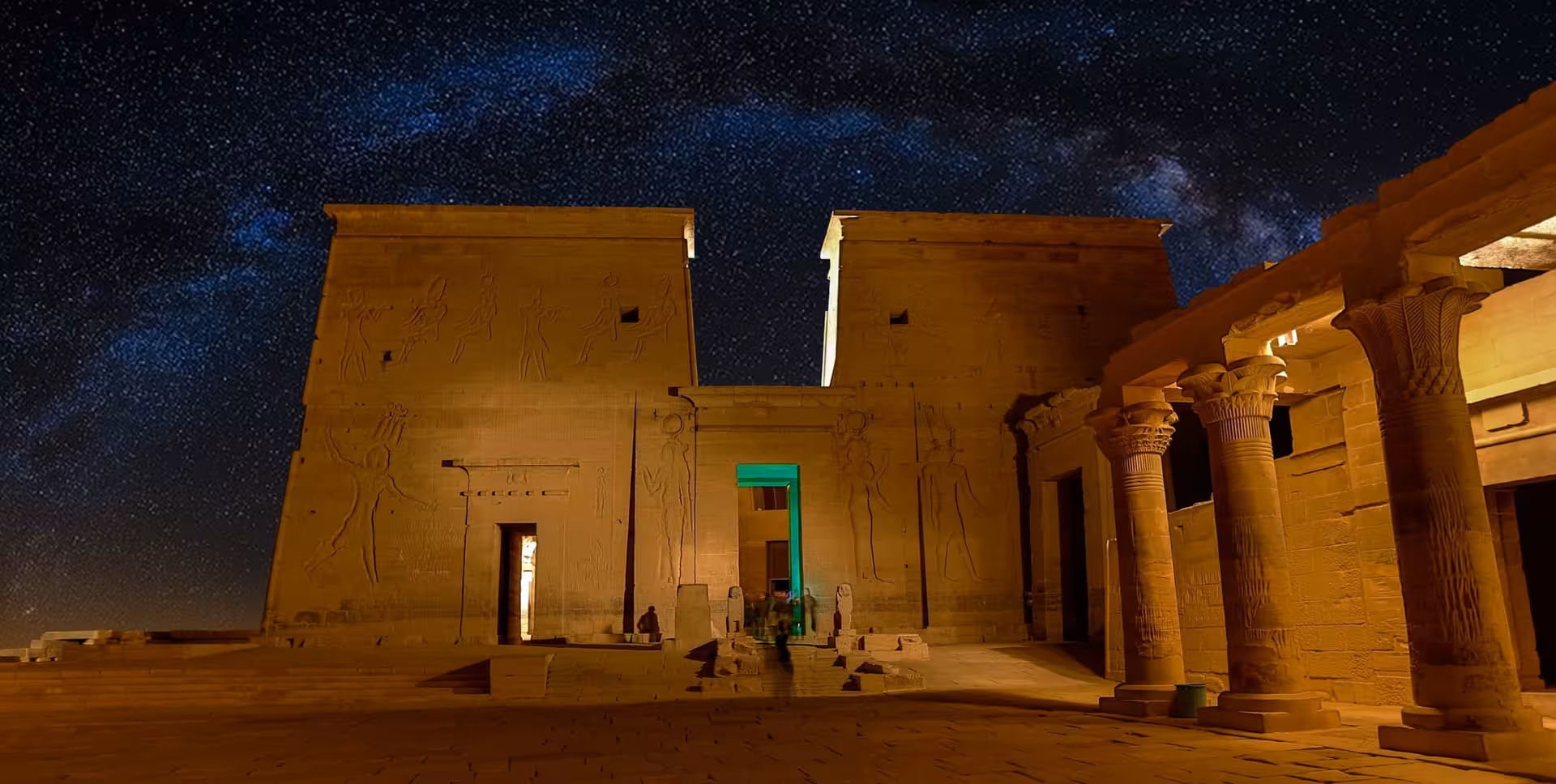 Close-up of Philae Temple during Aswan Sound and Light Show, golden columns under a starry night sky
