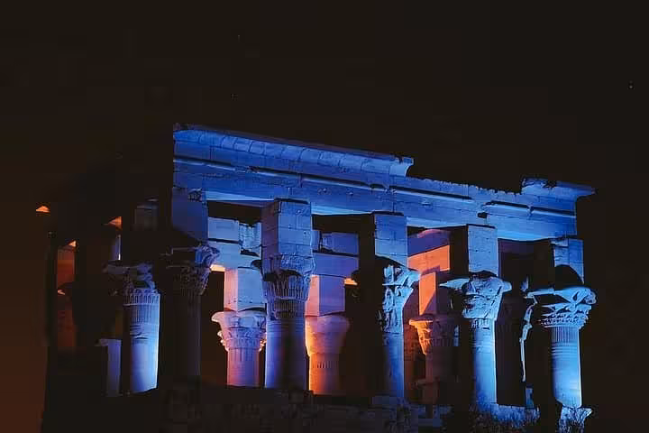 Colonnade of Philae Temple lit in blue and amber during the Sound and Light show, Aswan night tour experience