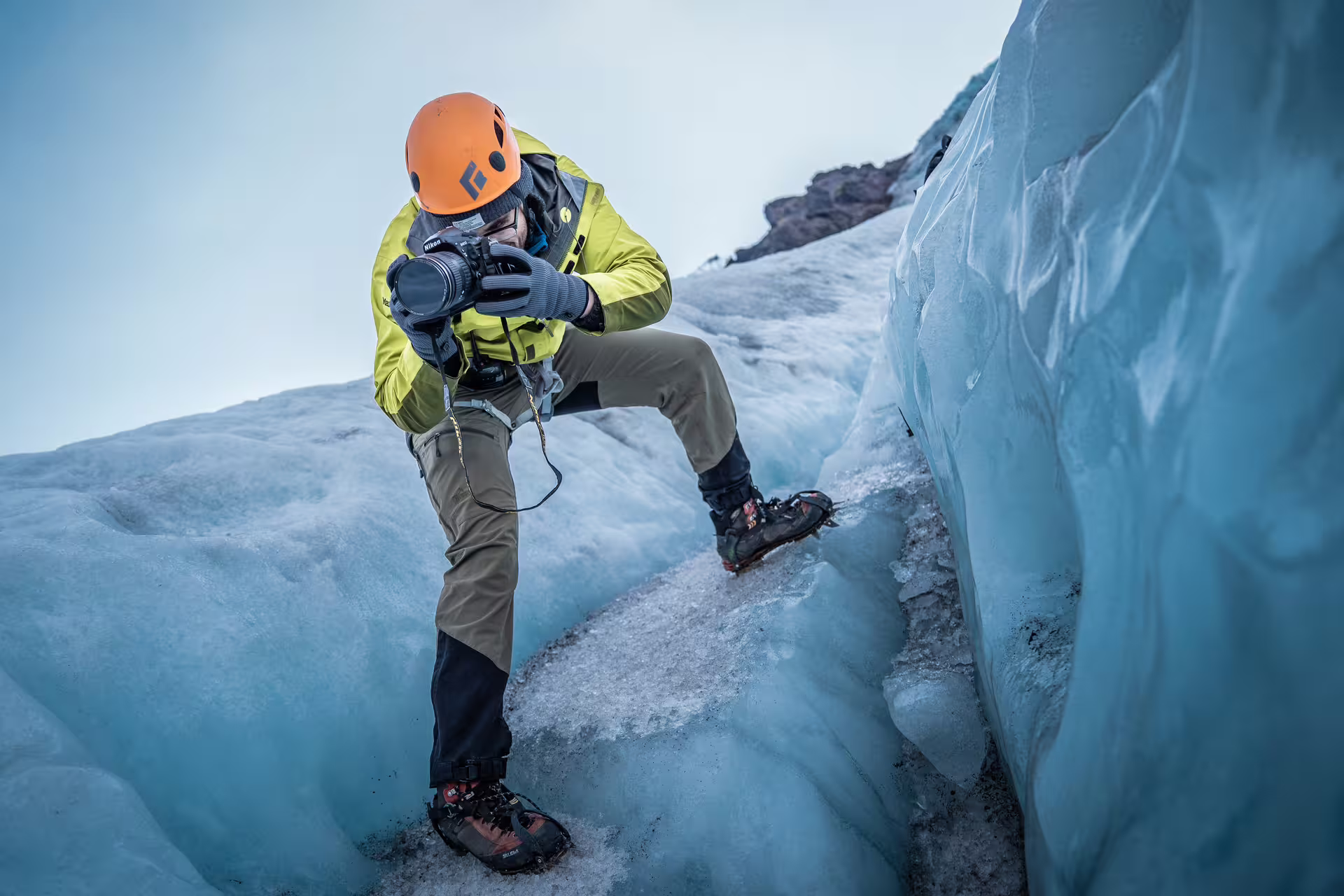 Photographer with helmet and crampons capturing shots during a private Iceland glacier ice cave guided tour with photos