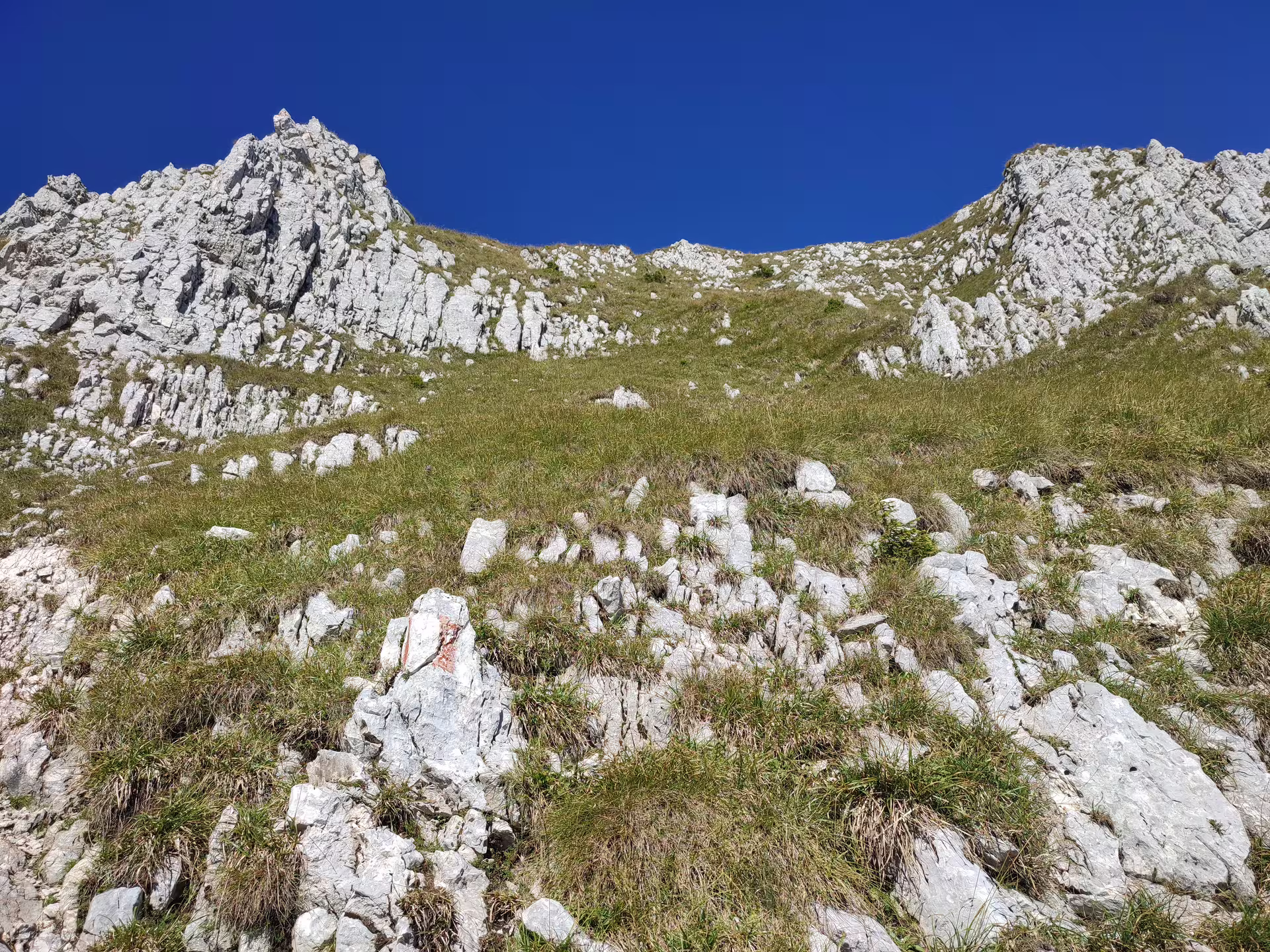 Rocky limestone slopes and jagged peaks of Piatra Craiului mountain under a clear blue sky