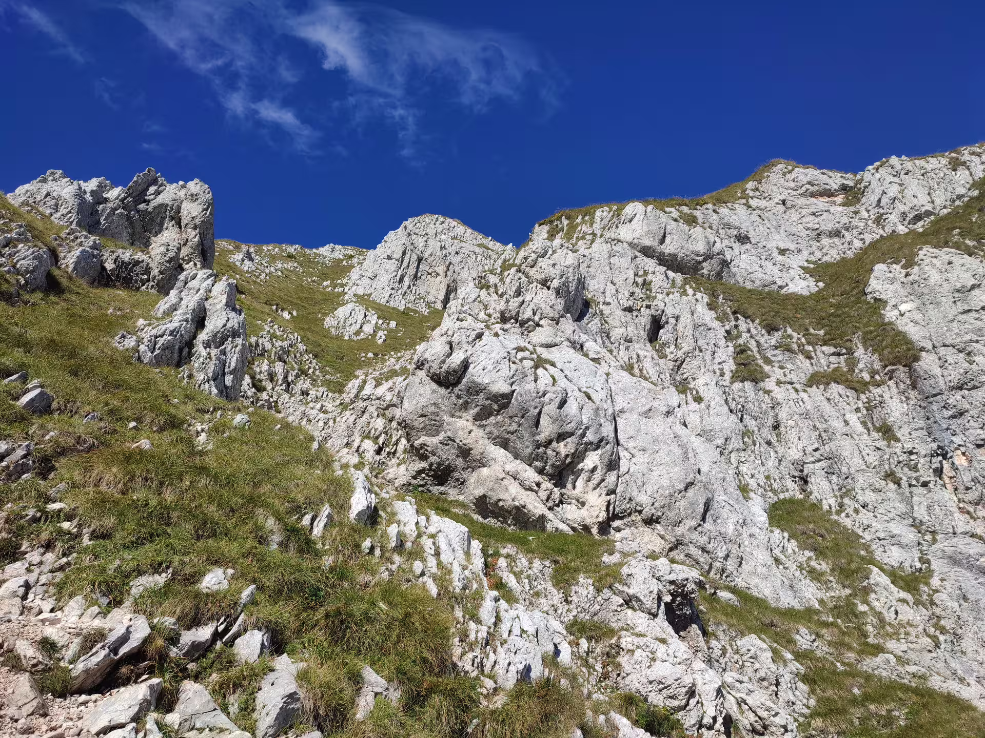Rocky limestone ridges and green alpine slopes of Piatra Craiului mountains under a clear blue sky