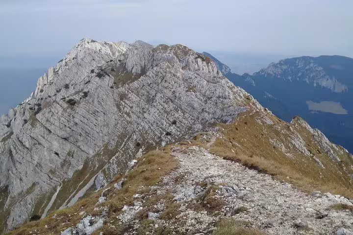 Rocky mountain ridge trail leading to limestone peak in Piatra Craiului Mountains, Romania