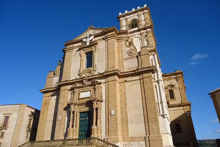 Discover the stunning facade of the historic Cathedral of Piazza Armerina under a clear blue Sicilian sky.