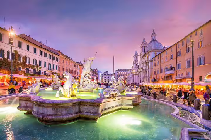 Piazza Navona fountain lit at dusk with lively cafés and baroque churches on a Rome by Night private chauffeured tour
