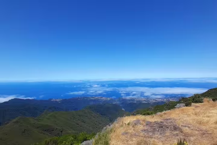 Stunning panoramic view from Pico Do Arieiro showcasing lush green valleys and a vast blue ocean under a clear sky.