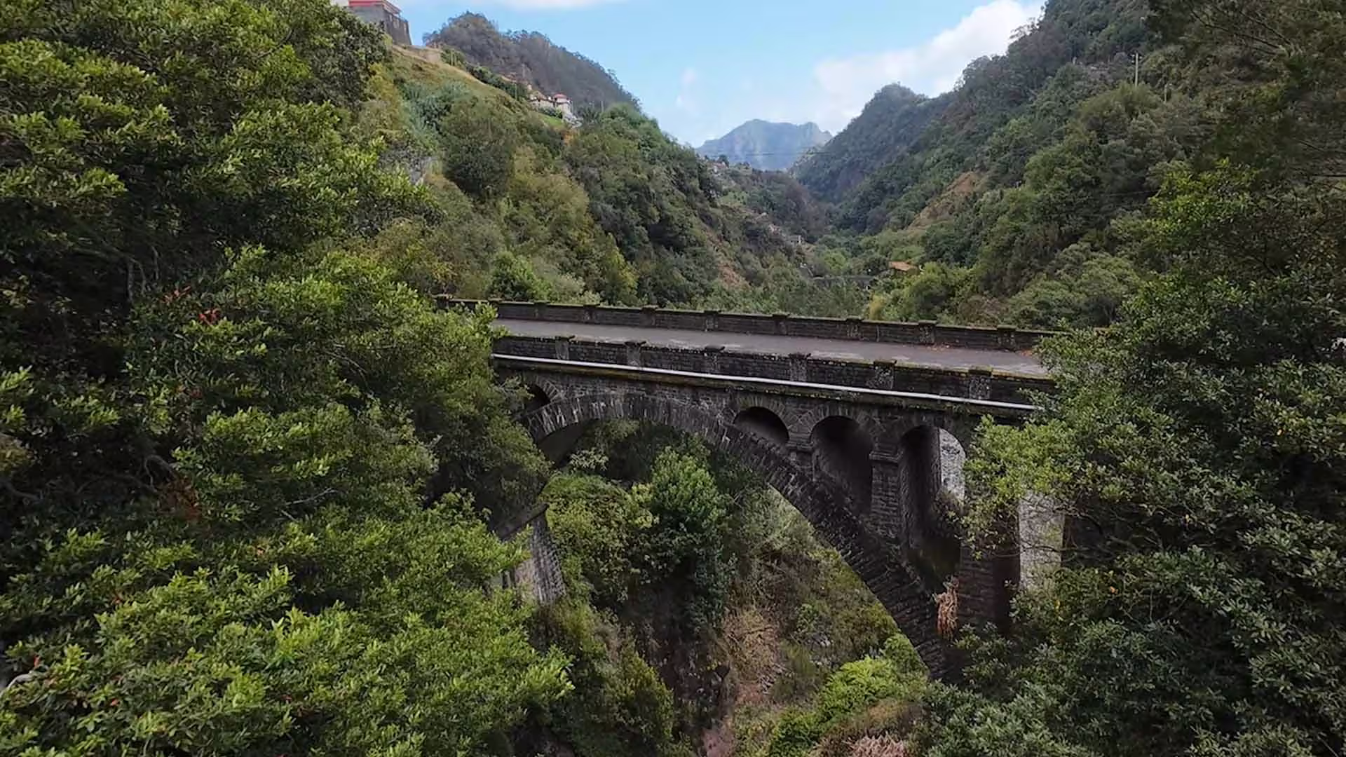 Scenic view of a historic stone bridge surrounded by lush greenery on the Pico do Arieiro and Santana full-day tour.