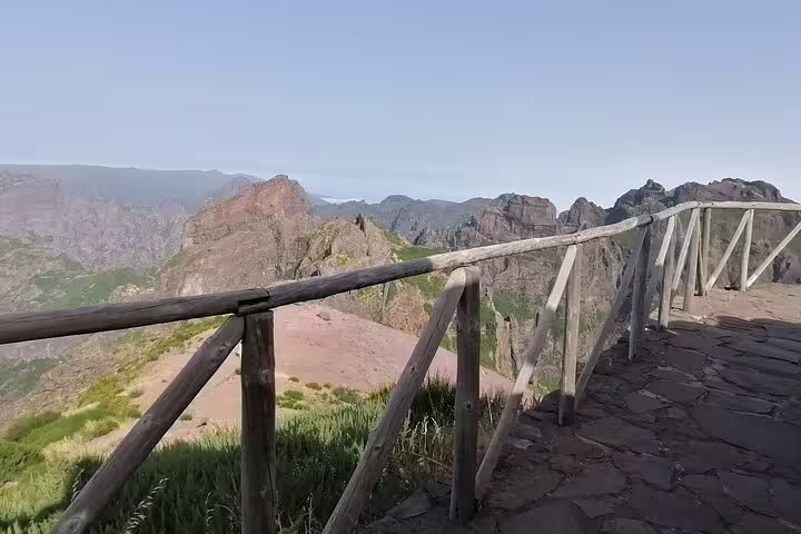 Wooden railing along the Pico do Arieiro trail offers stunning panoramic mountain views on a clear day.