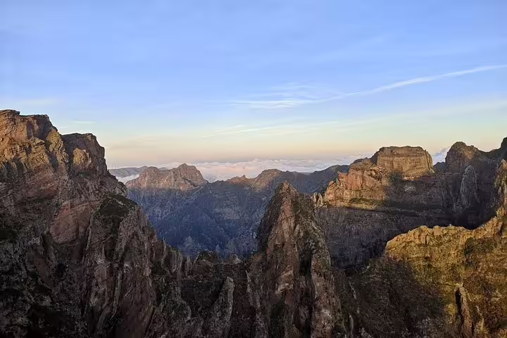 Breathtaking sunrise panorama of Pico do Arieiro's rugged cliffs and valleys, perfect for a self-guided hike adventure.