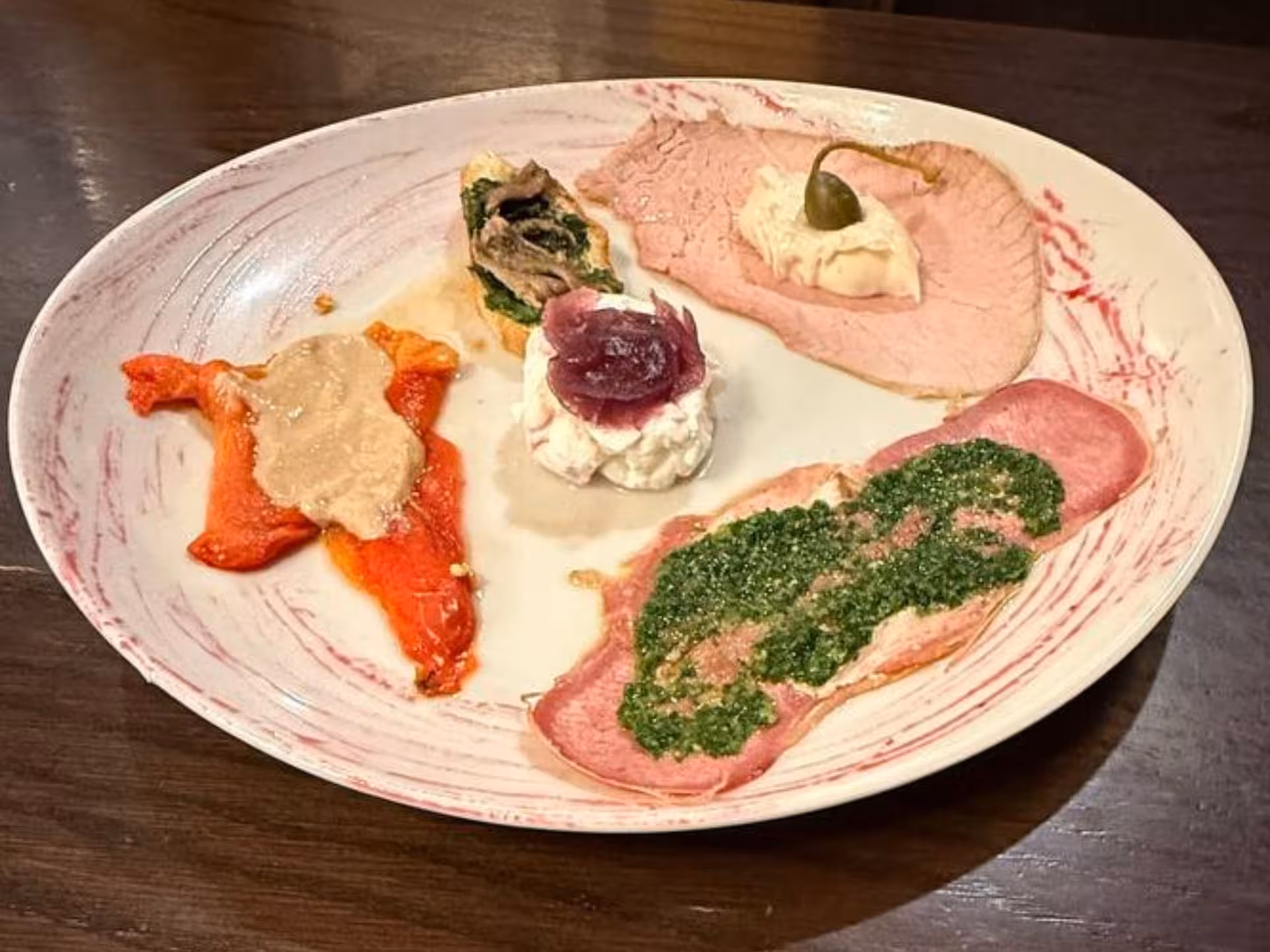 Assorted Piedmontese tapas with vibrant sauces and garnishes on a white plate, perfect for Turin culinary tours.