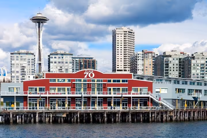Pier 70 waterfront building in Seattle with Space Needle visible in the background against cloudy sky