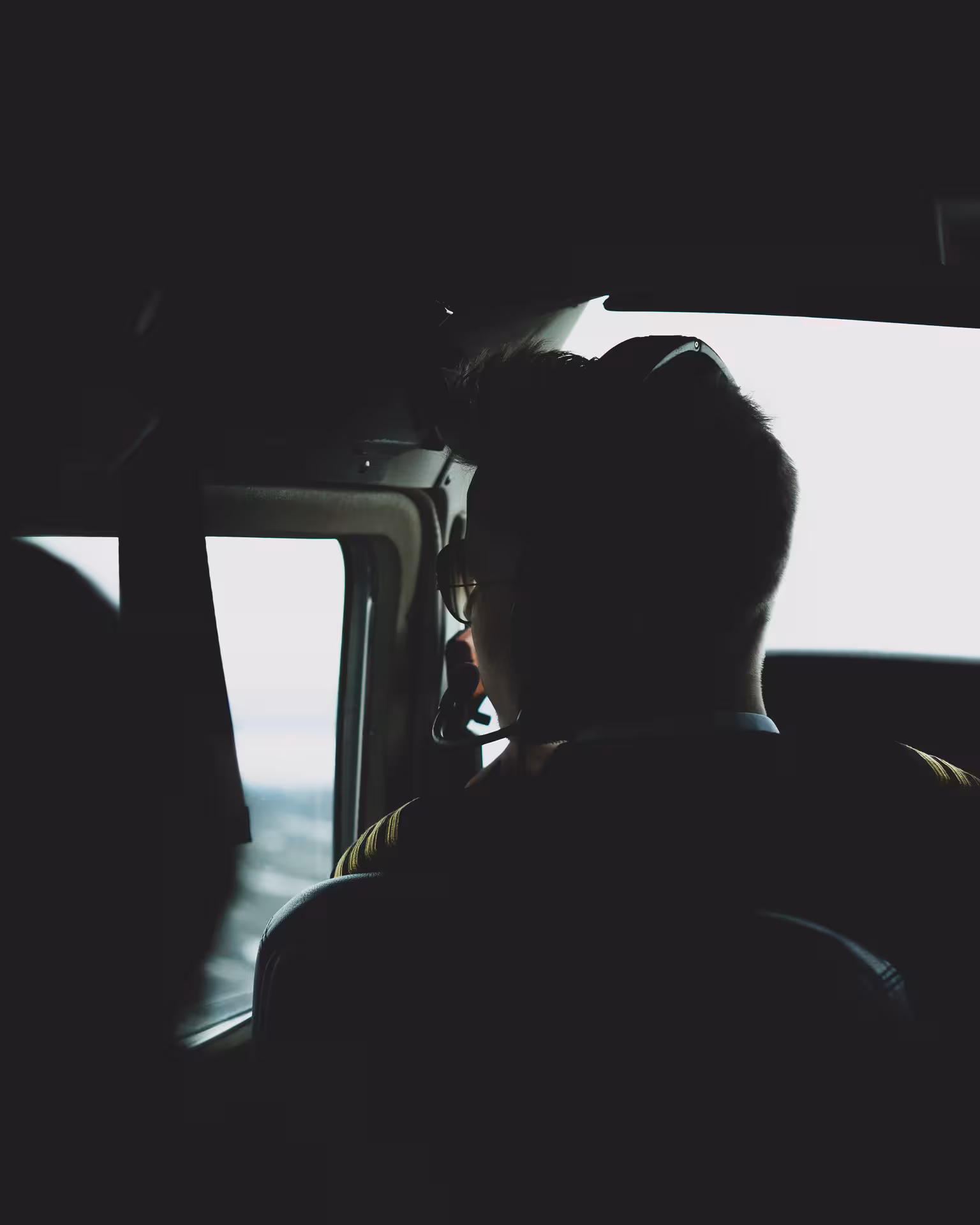 Pilot wearing headset in cockpit during aerial flight over Icelandic glacial landscape