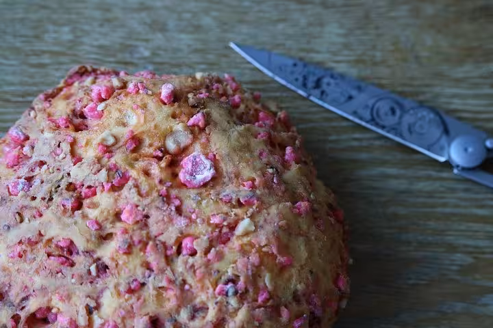 Close-up of a pink praline brioche and a knife on a wooden table at Les Halles Paul Bocuse, showcasing local French cuisine.