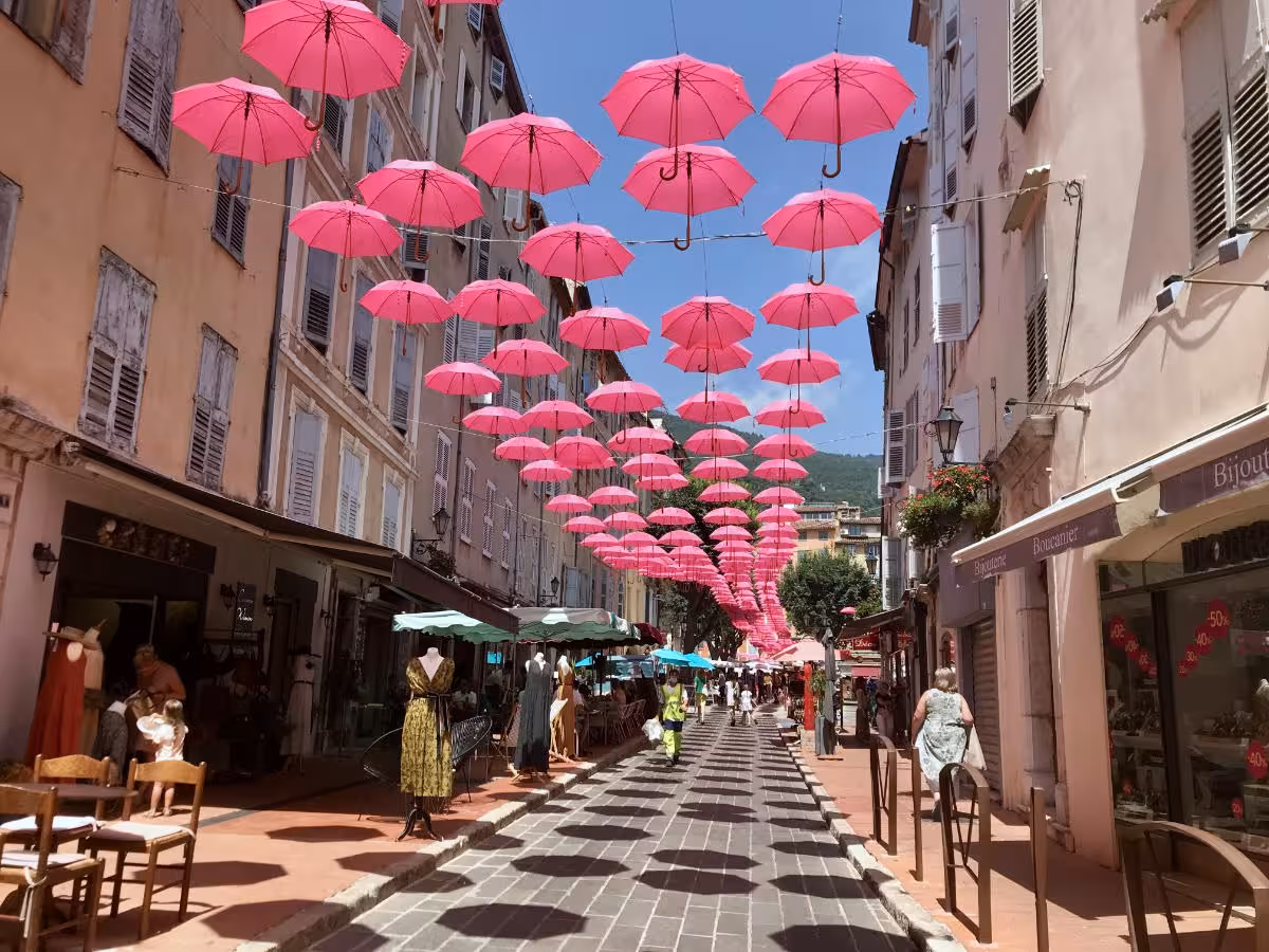 Pink umbrellas hanging over a charming pedestrian street in Grasse, Provence, France