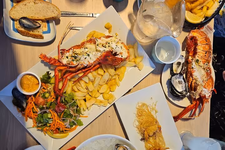 Delicious seafood platter with lobster, oysters, and fries served on a Pinnacle Day Adventure Tour dining experience.