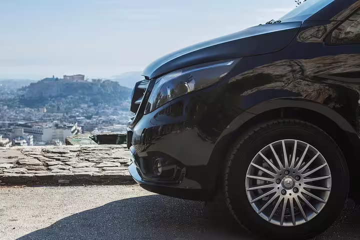 Private transfer vehicle near Athens skyline for Piraeus port to hotel arrival, reliable chauffeur service