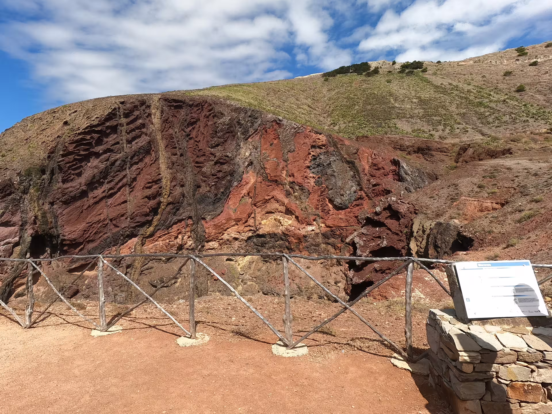 Vibrant red and brown rocky landscape on a sunny day, showcasing the rugged terrain of the Pirate Expedition Island Tour.