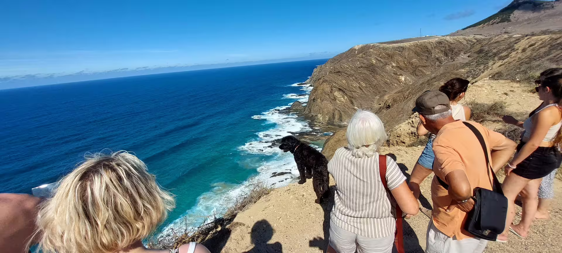 Tourists enjoy breathtaking ocean views on a cliffside stop during the Pirate Expedition: Full Island Tour adventure.