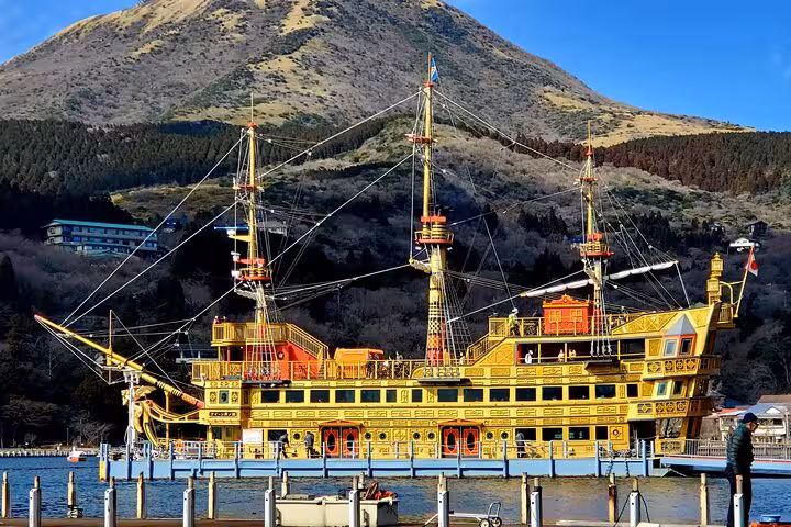 Gold ornate pirate ship docked at Lake Ashi Hakone with scenic mountain backdrop on 2-day Tokyo Mt Fuji tour