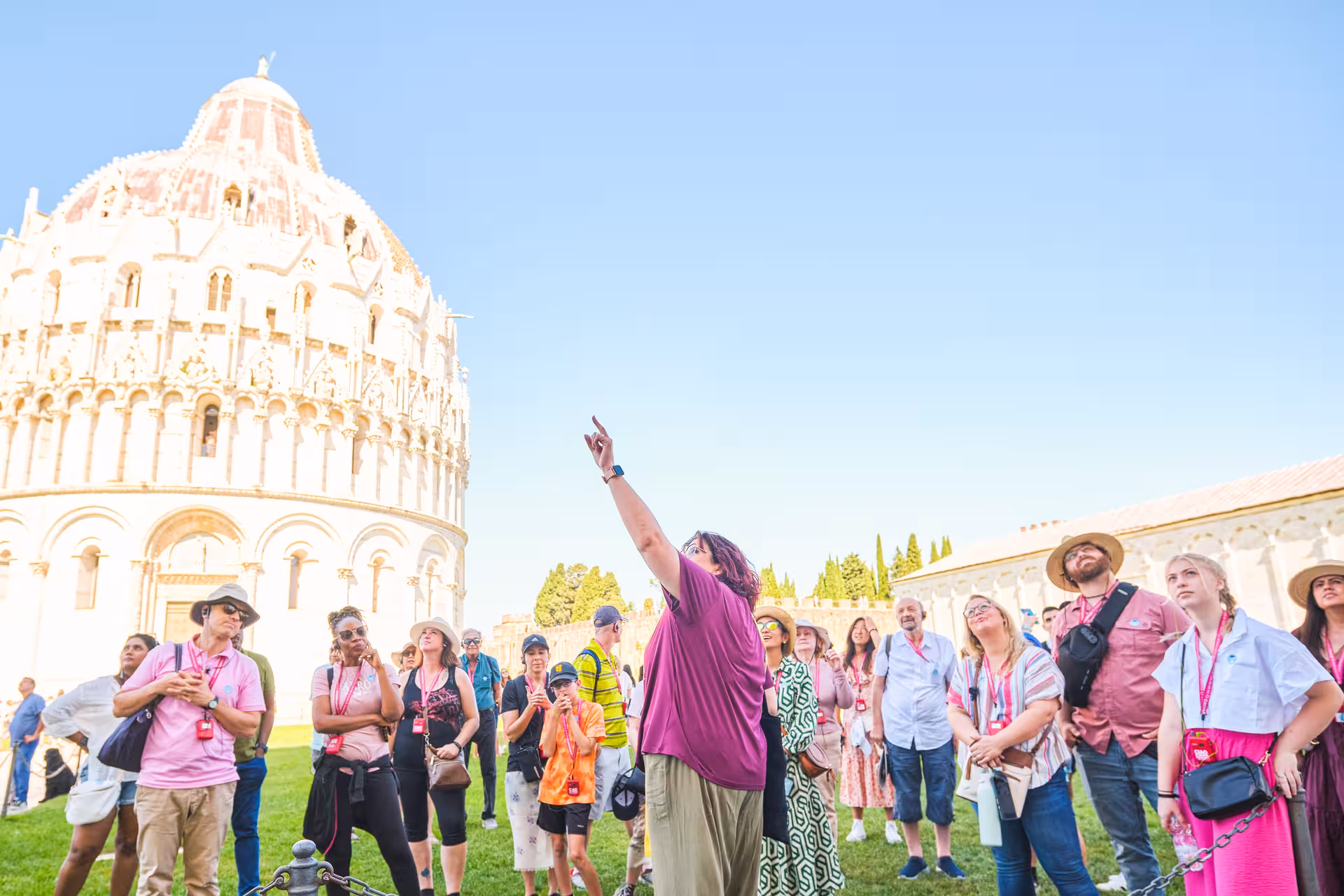 Tourists listen to a guide in front of Pisa's Baptistery during a full day shore excursion from Livorno.