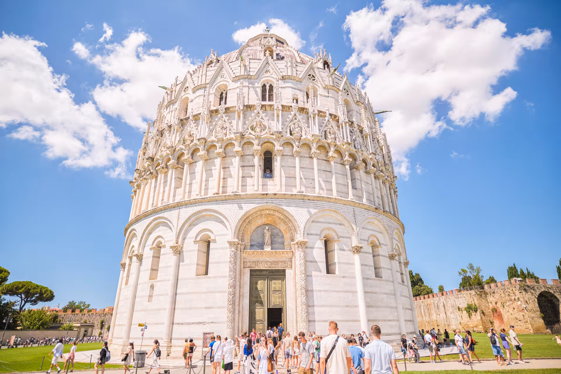 Tourists gather outside the Pisa Baptistery, a stunning example of Romanesque architecture in Piazza dei Miracoli.